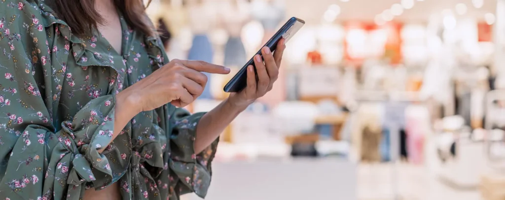 Una mujer hace uso de su teléfono ilustrando la importancia de Desarrollar una Tienda Online